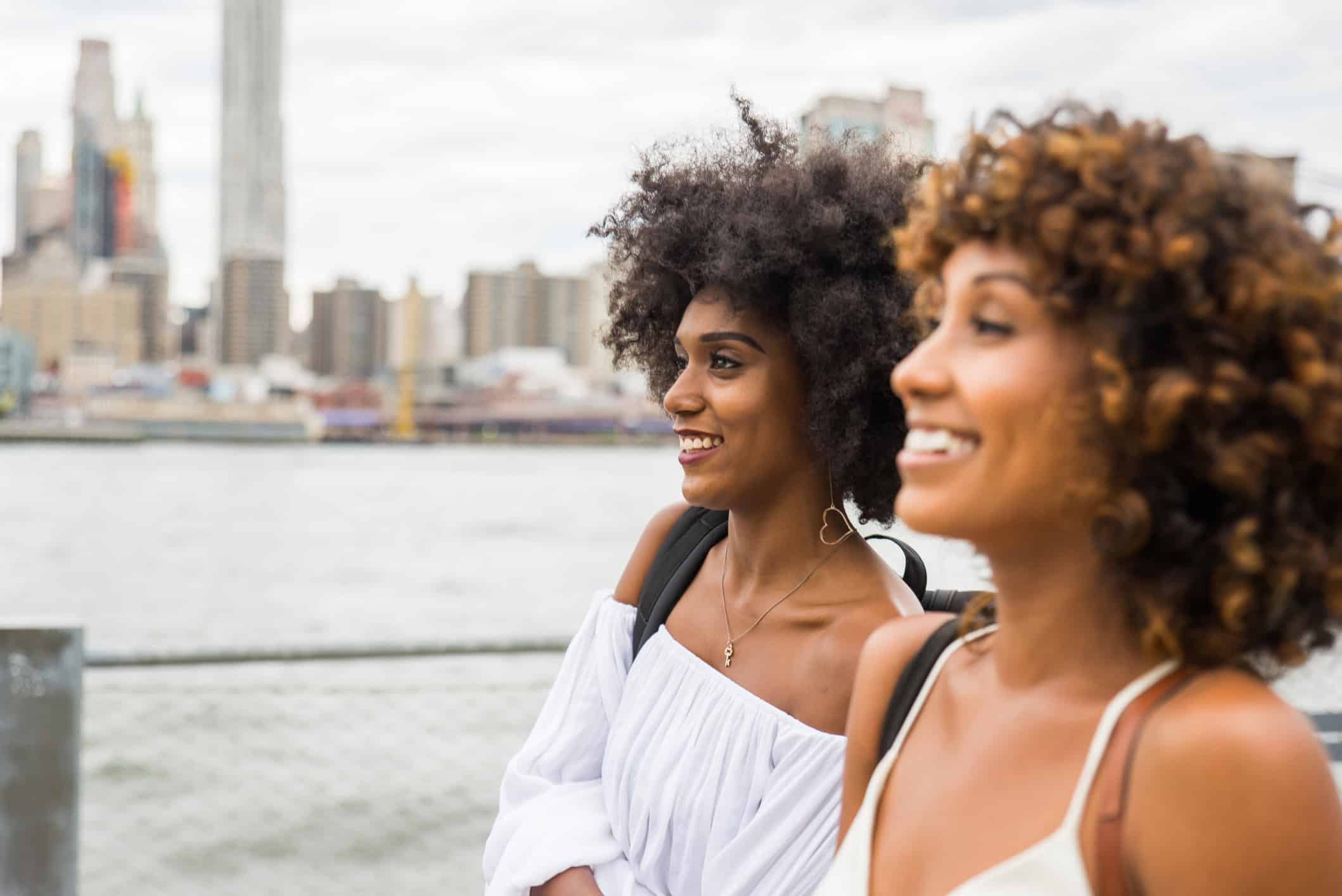 Women smile walking with NYC in the background
