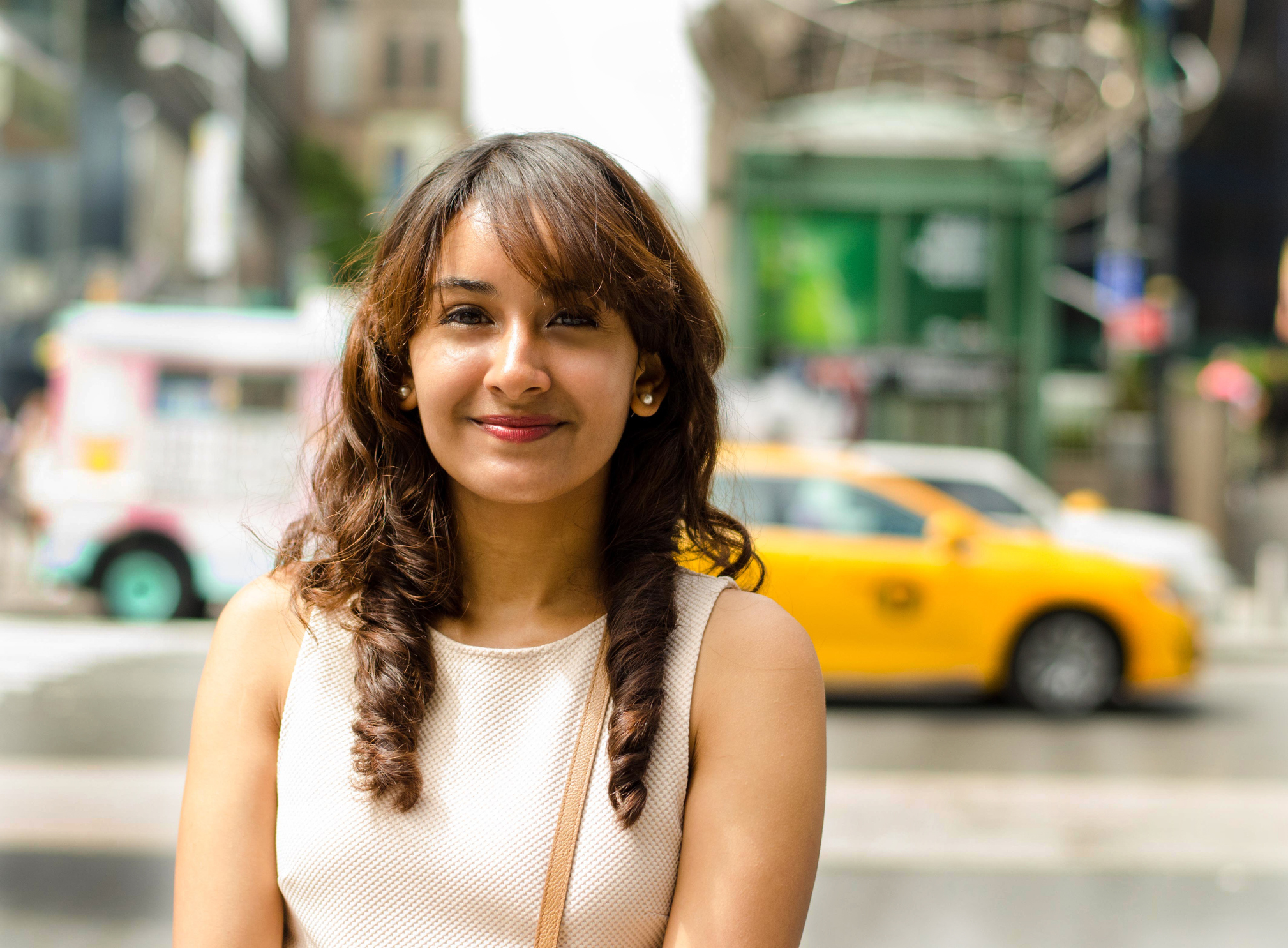 Pretty girl smiling in the city with taxi in the background